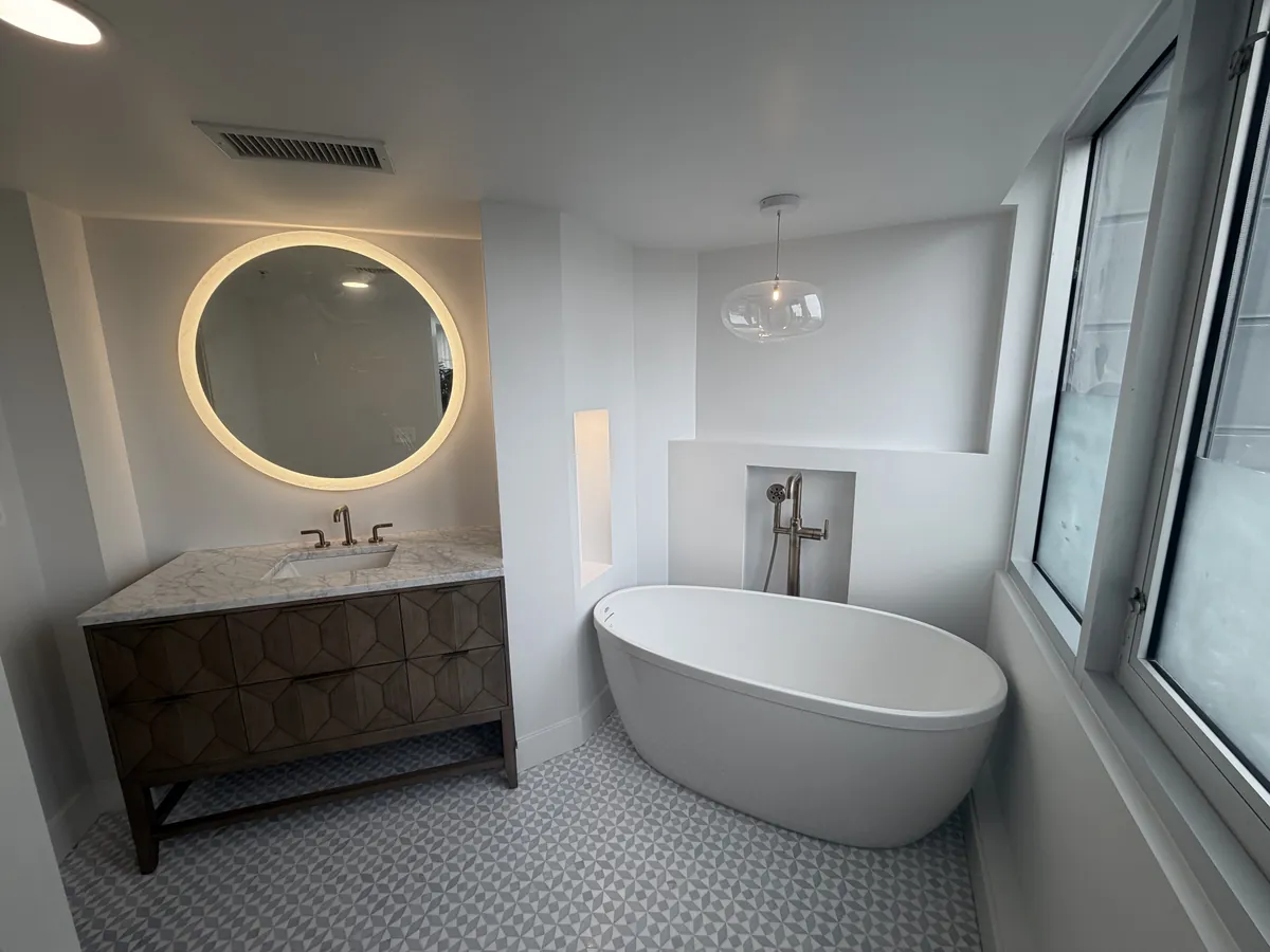 Freestanding tub with backlit mirror and hex mosaic floor