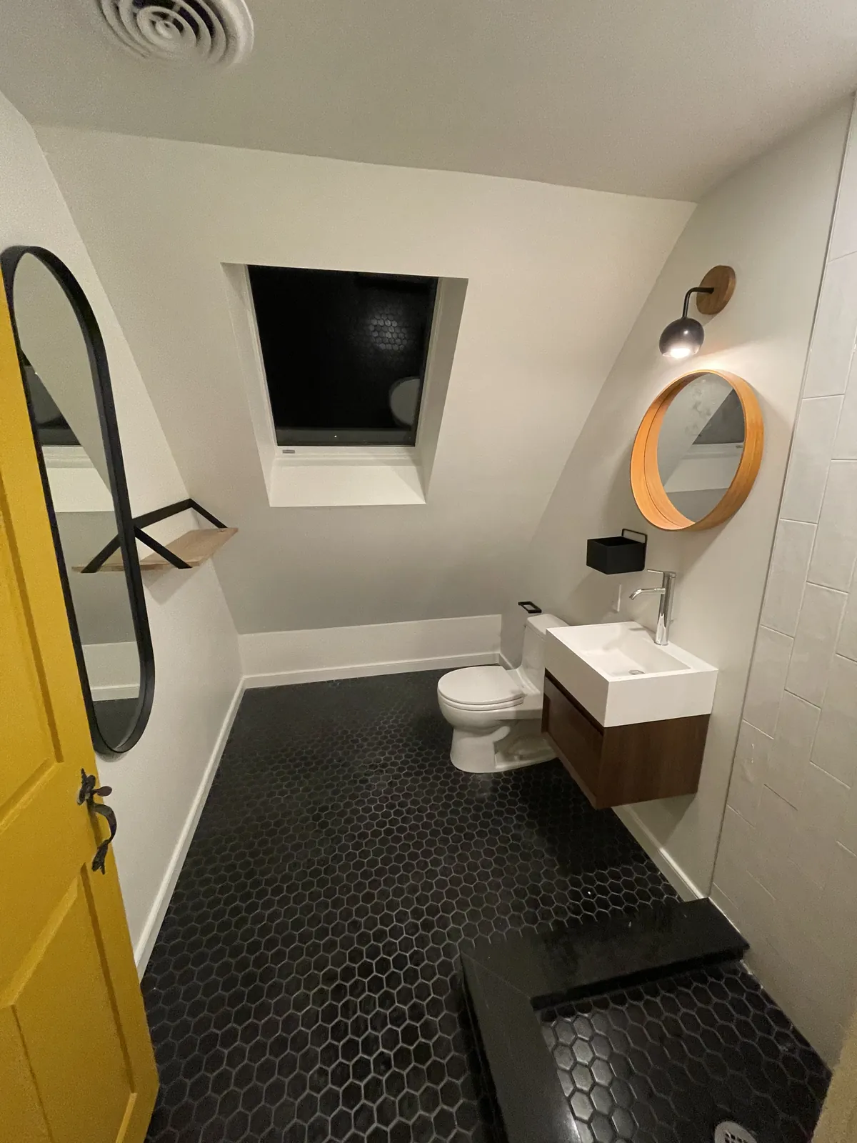 Attic bath with black hex tile and skylight