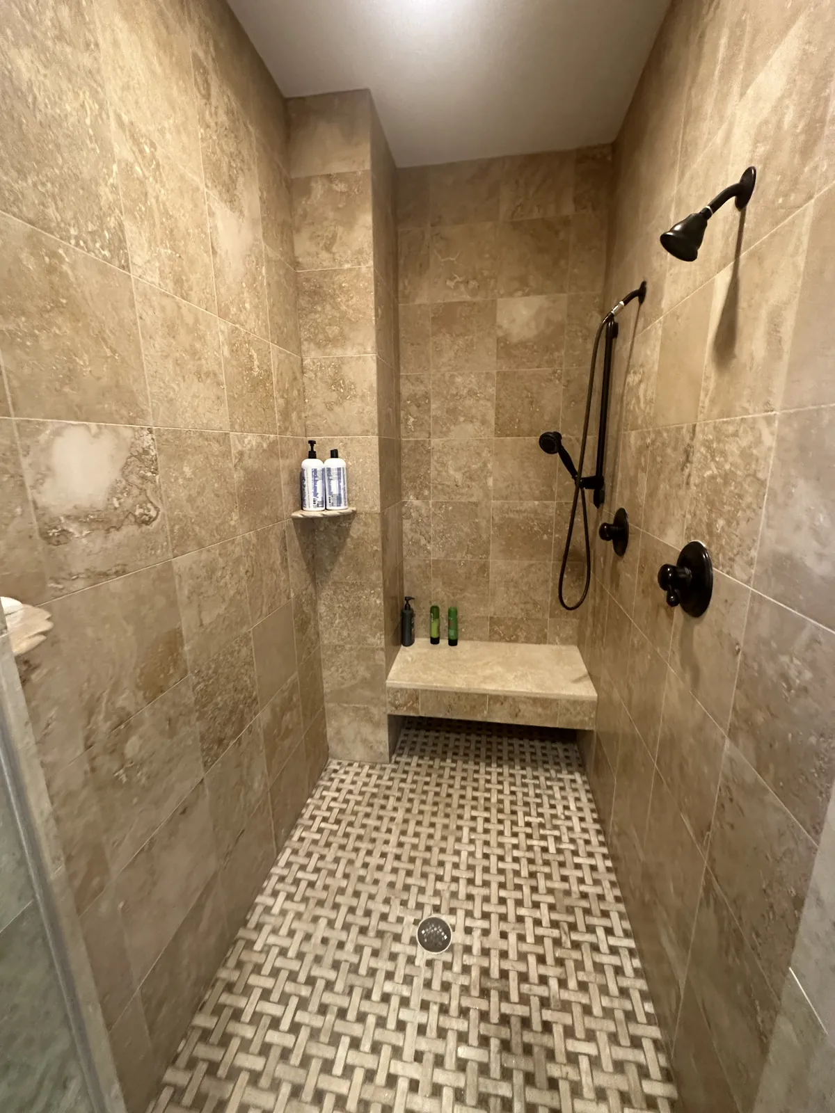 Travertine shower with bench and basketweave floor